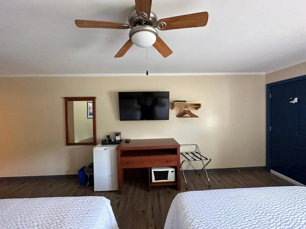 Guest room with a wall-mounted TV, mini-fridge, microwave and two beds